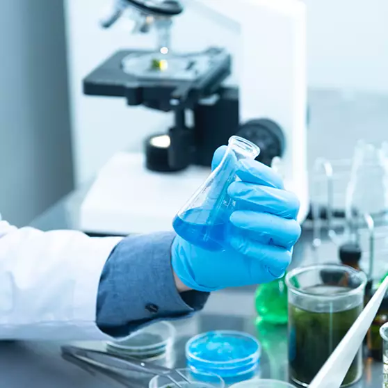STAO works with Leading With Nice working with a beaker while wearing gloves